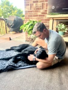 Logan holding Clydey, a black dog, in his arms